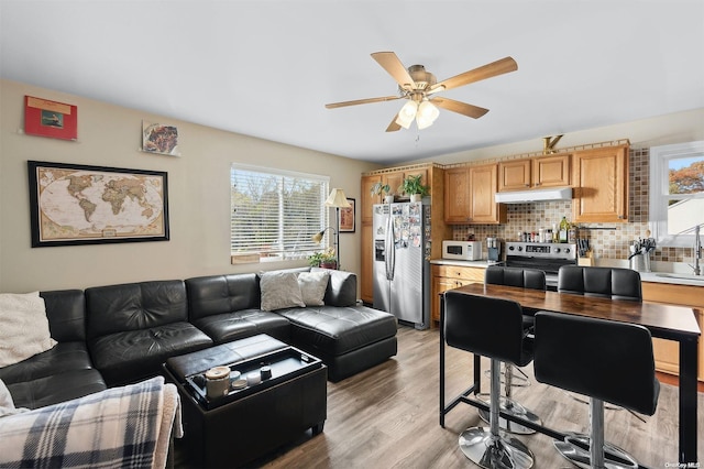 living room with light hardwood / wood-style flooring, ceiling fan, and sink