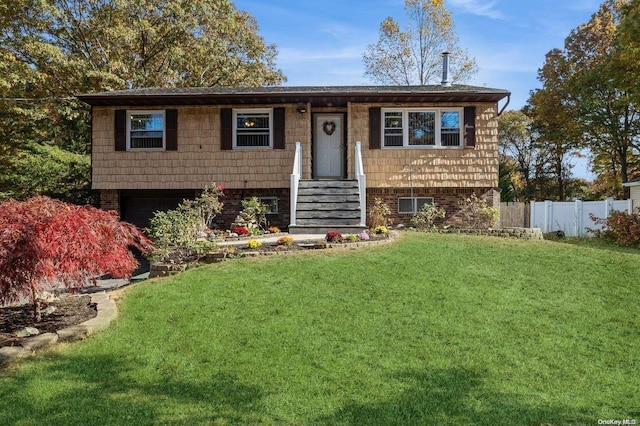 raised ranch featuring a garage and a front lawn