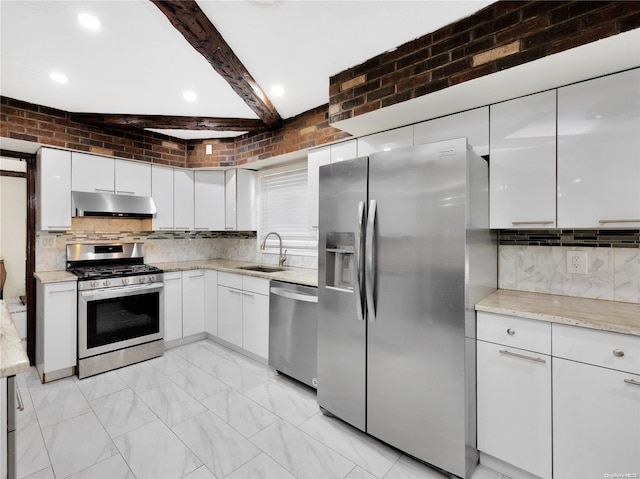 kitchen featuring appliances with stainless steel finishes, brick wall, sink, beam ceiling, and white cabinets