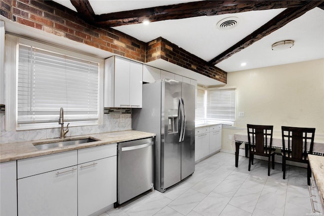 kitchen with beam ceiling, sink, white cabinetry, and stainless steel appliances