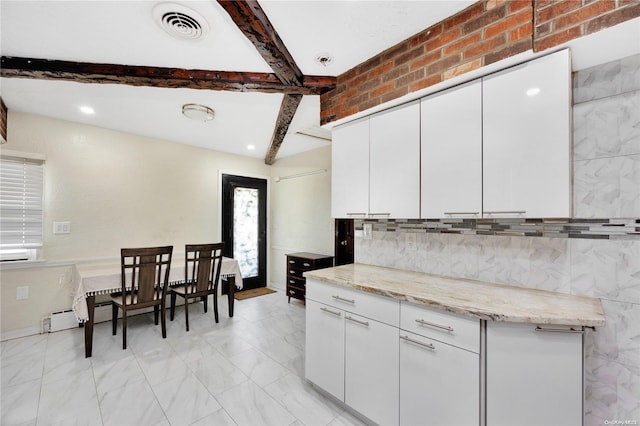 kitchen with light stone counters, brick wall, a baseboard heating unit, beam ceiling, and white cabinetry