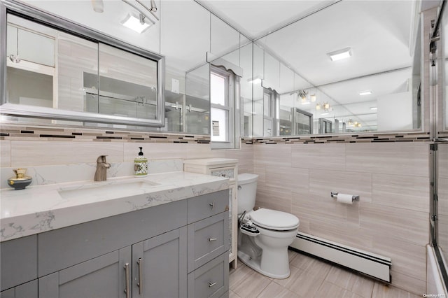 bathroom featuring a baseboard radiator, tile patterned floors, toilet, vanity, and tile walls