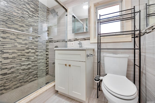 bathroom featuring vanity, a shower with shower door, tile walls, and toilet