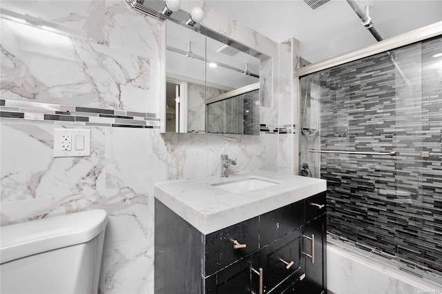 bathroom featuring vanity, toilet, and tile walls