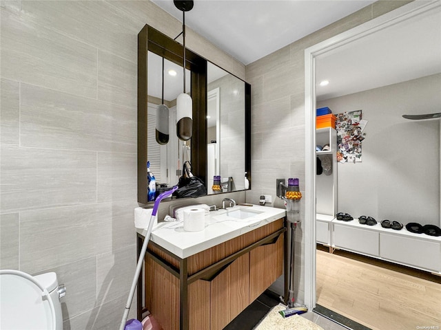 bathroom featuring hardwood / wood-style flooring, vanity, and tile walls