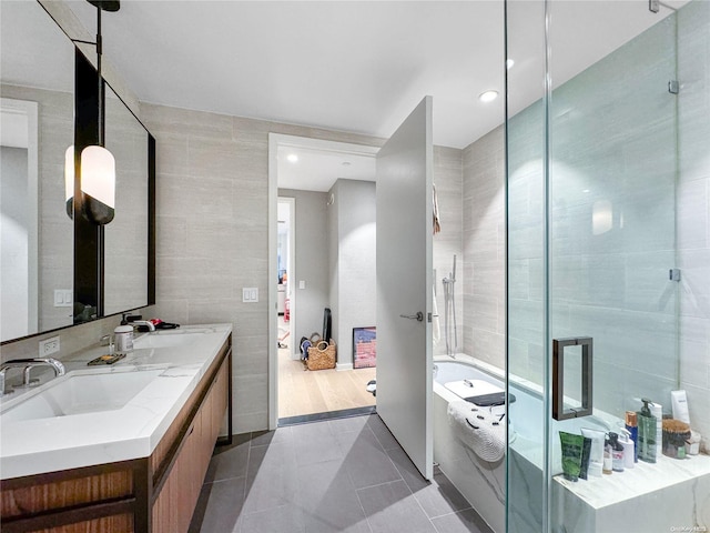 bathroom featuring tile patterned flooring, vanity, separate shower and tub, and tile walls