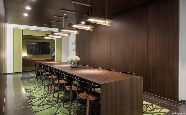 bar with wood walls and dark brown cabinetry