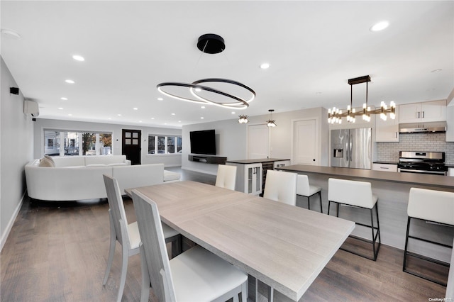 dining area featuring dark hardwood / wood-style flooring, an inviting chandelier, and a wall mounted AC