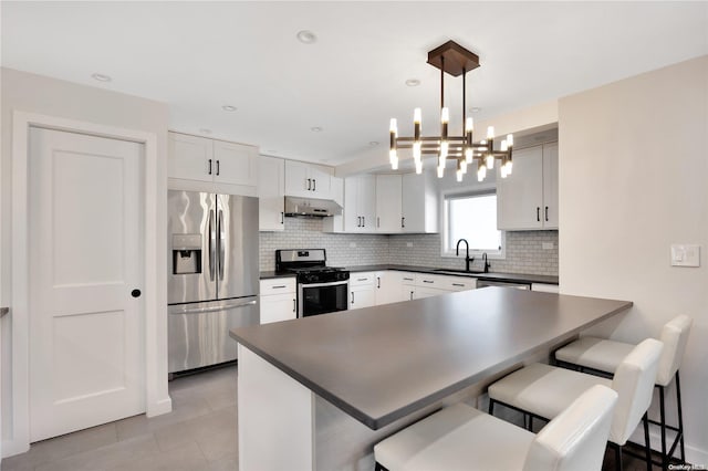 kitchen featuring ventilation hood, a breakfast bar, white cabinets, and appliances with stainless steel finishes