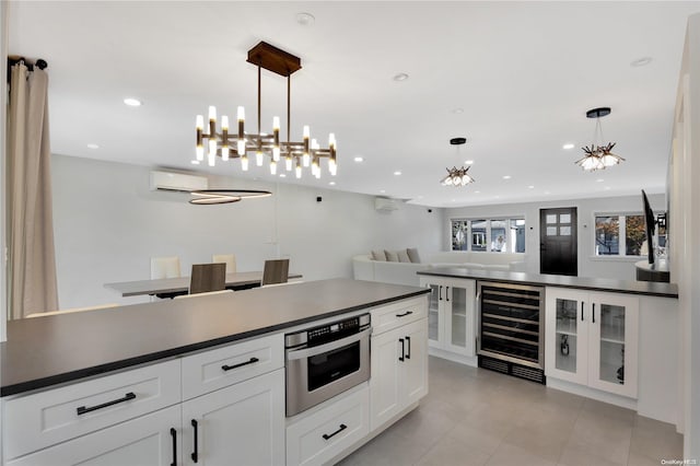 kitchen with white cabinetry, beverage cooler, a wall mounted AC, decorative light fixtures, and appliances with stainless steel finishes