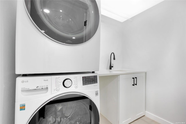 washroom with stacked washer and dryer, cabinets, and sink