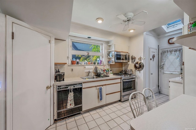 kitchen with appliances with stainless steel finishes, a skylight, tasteful backsplash, light tile patterned floors, and white cabinetry