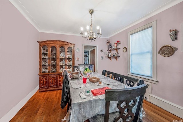 dining space with hardwood / wood-style floors, ornamental molding, and a notable chandelier