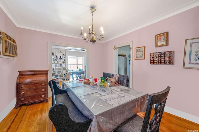 dining area featuring hardwood / wood-style flooring, an inviting chandelier, and crown molding