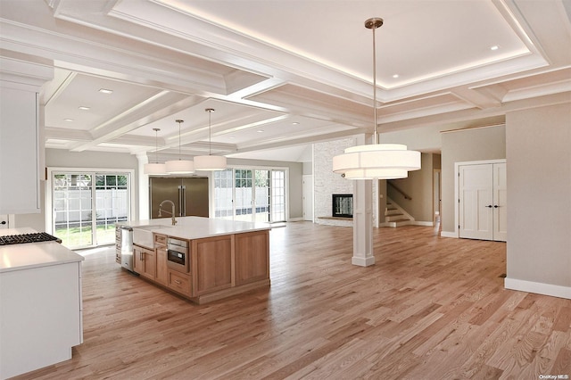 kitchen with a large island, light hardwood / wood-style flooring, pendant lighting, high quality fridge, and a fireplace