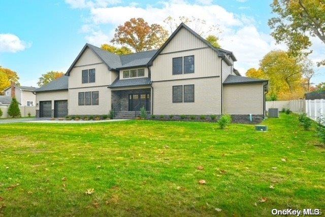 back of property featuring cooling unit, a garage, and a yard