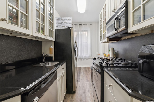 kitchen featuring sink, hardwood / wood-style flooring, decorative backsplash, appliances with stainless steel finishes, and white cabinetry