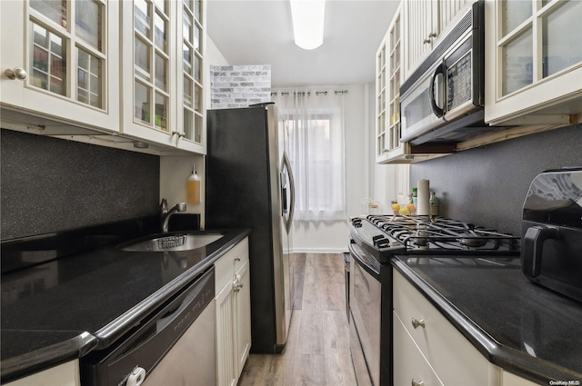 37-21 80th St Unit 3M, Jackson Heights, NY 11372 - kitchen with stainless steel appliances, a sink, dark countertops, light wood finished floors, and glass insert cabinets