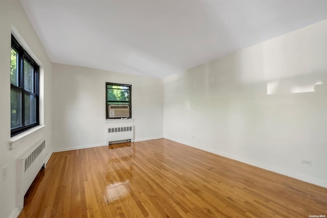 unfurnished living room with a wealth of natural light, radiator, and light hardwood / wood-style flooring