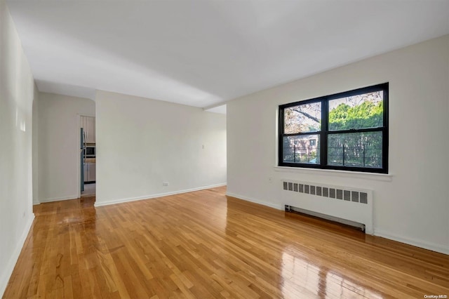 unfurnished room featuring light hardwood / wood-style floors and radiator