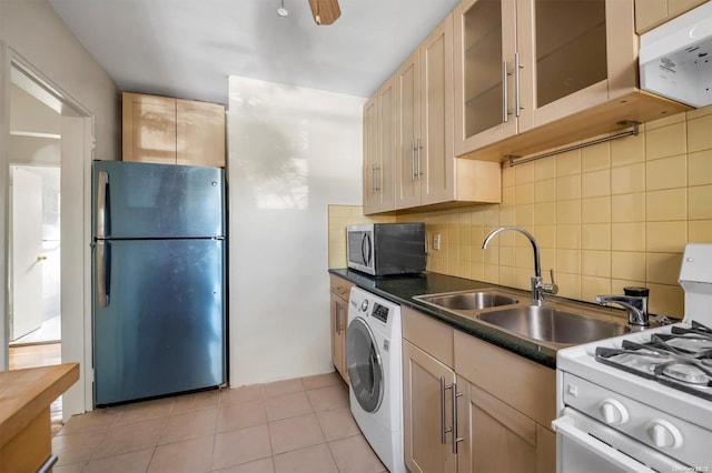 kitchen featuring sink, decorative backsplash, light tile patterned flooring, stainless steel appliances, and washer / clothes dryer