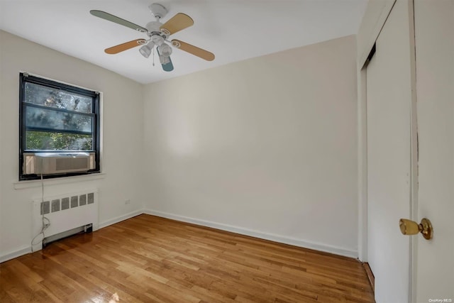 unfurnished bedroom with radiator, ceiling fan, cooling unit, light hardwood / wood-style floors, and a closet