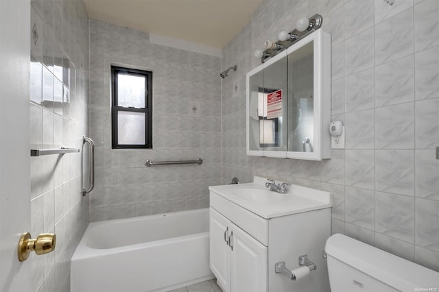 full bathroom featuring vanity, toilet, tile walls, and tiled shower / bath combo