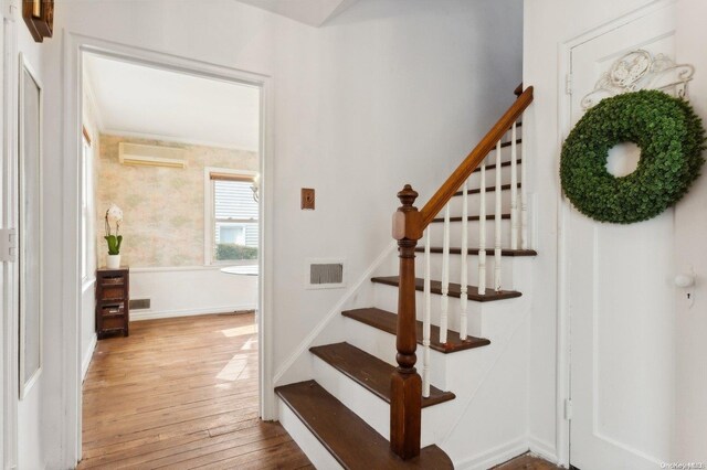 staircase with wood-type flooring and a wall mounted air conditioner