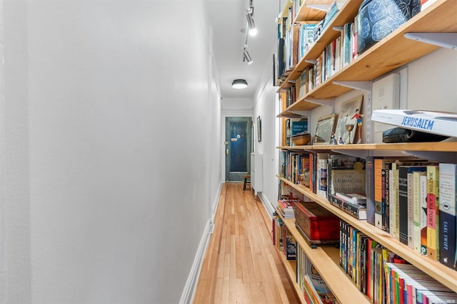 hallway with wood-type flooring and rail lighting