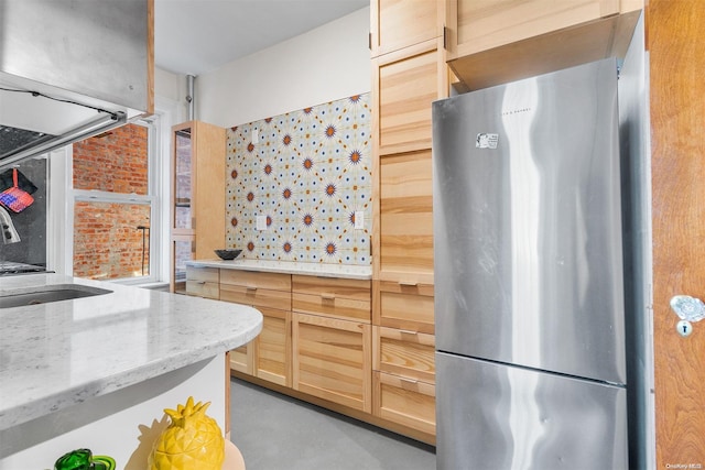 kitchen with brick wall, stainless steel fridge, concrete floors, and sink