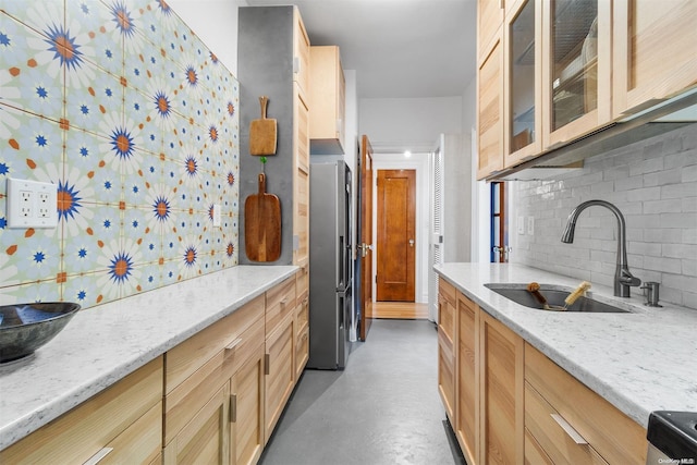 kitchen with light stone countertops, appliances with stainless steel finishes, tasteful backsplash, sink, and light brown cabinets