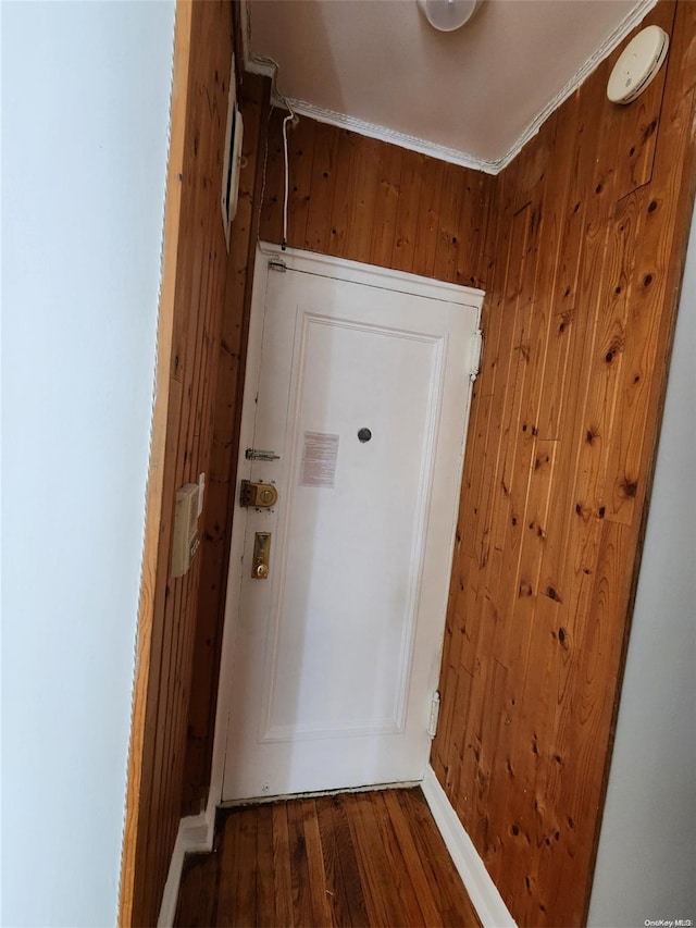 entryway featuring wood-type flooring, crown molding, and wooden walls