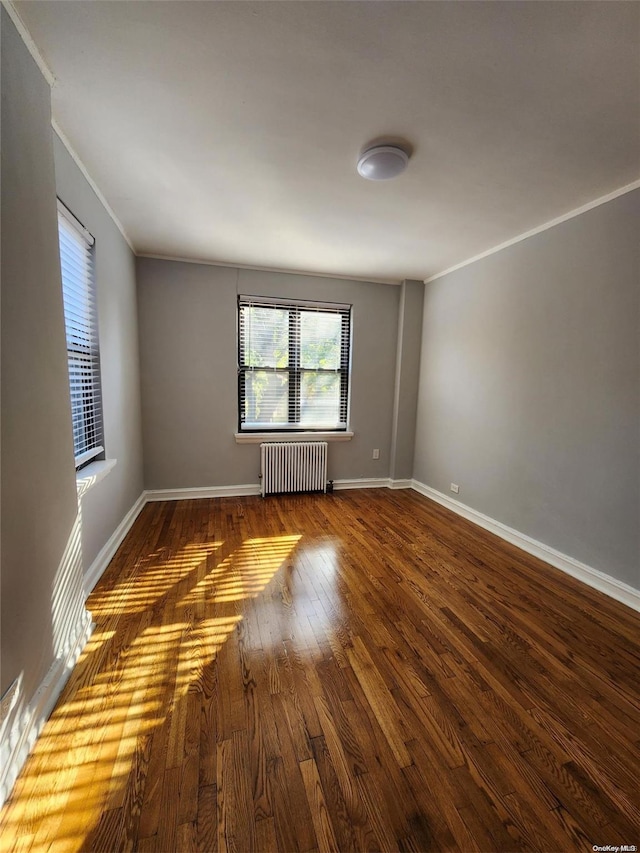 unfurnished room featuring radiator heating unit, dark wood-type flooring, and ornamental molding