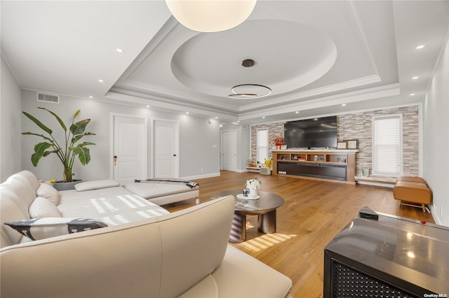 living room featuring a tray ceiling, light hardwood / wood-style flooring, and crown molding