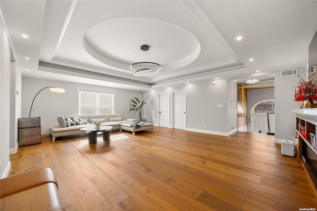 living room with a tray ceiling and light hardwood / wood-style floors