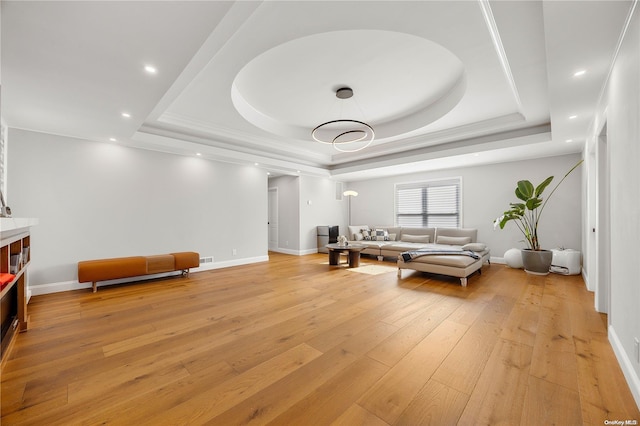 living room with a tray ceiling and light hardwood / wood-style flooring