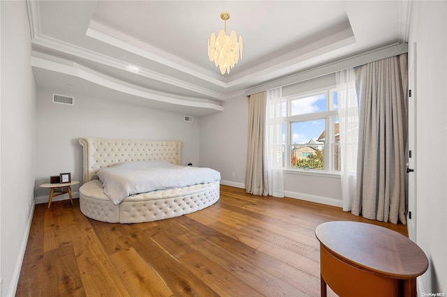 bedroom featuring a chandelier, wood-type flooring, and a tray ceiling