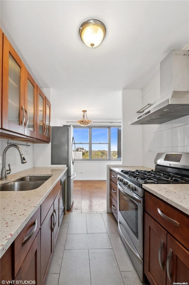 kitchen featuring backsplash, sink, wall chimney exhaust hood, light stone countertops, and stainless steel appliances