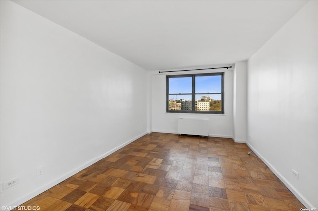 unfurnished room featuring radiator heating unit and parquet flooring