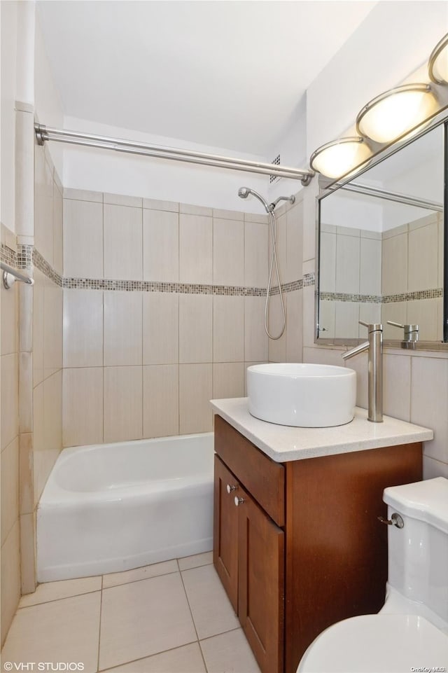 full bathroom with vanity, tile patterned floors, tiled shower / bath combo, toilet, and tile walls