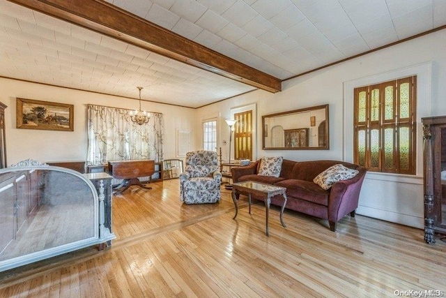 living room with wood-type flooring, a wealth of natural light, a notable chandelier, and beam ceiling