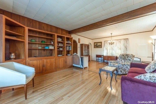 living room with beam ceiling, wood walls, light hardwood / wood-style flooring, and a notable chandelier