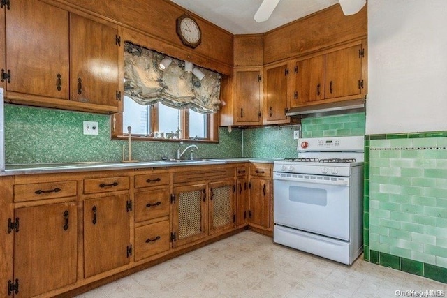 kitchen featuring decorative backsplash, white gas range oven, ceiling fan, and sink