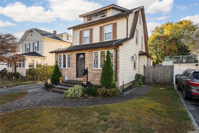 view of front of property featuring a wall mounted AC and a front lawn