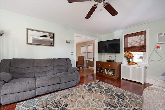 living room with dark hardwood / wood-style flooring, a wall unit AC, radiator, and ceiling fan