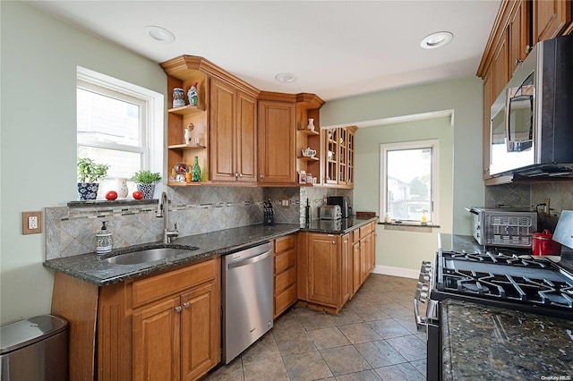 kitchen with sink, dark stone countertops, tasteful backsplash, light tile patterned flooring, and stainless steel appliances