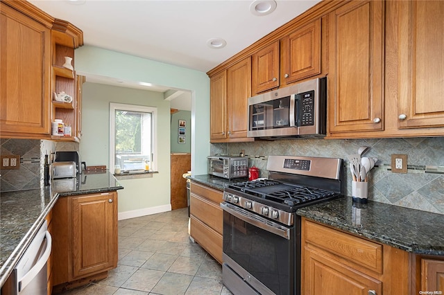 kitchen with decorative backsplash, dark stone countertops, light tile patterned floors, and stainless steel appliances