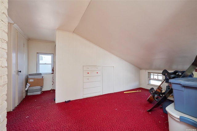 additional living space featuring dark carpet and vaulted ceiling