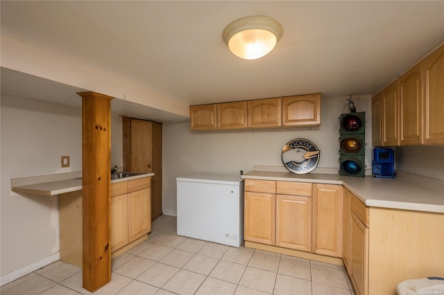 kitchen with light brown cabinetry, light tile patterned floors, and fridge