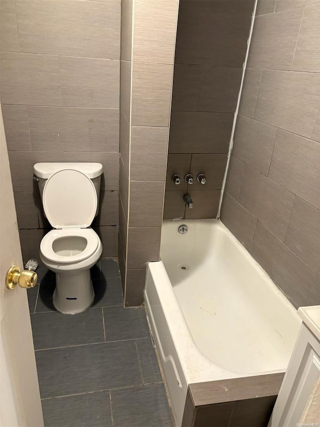 bathroom featuring vanity, tile patterned floors, toilet, tile walls, and a tub